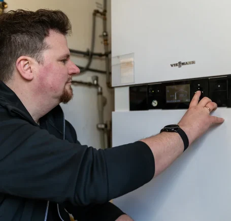 Praxisnahe Energieberatung: SHK-Meister De Gauß bei handwerklichen Arbeiten an Gebäudetechnik