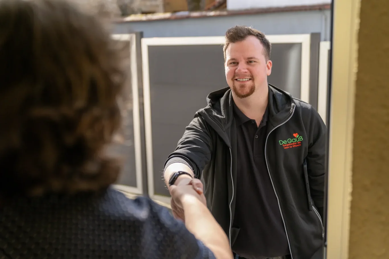 Energieberater Dennis Gauß begrüßt eine Kundin persönlich an der Haustür zur Vor-Ort-Energieberatung in Mainz.